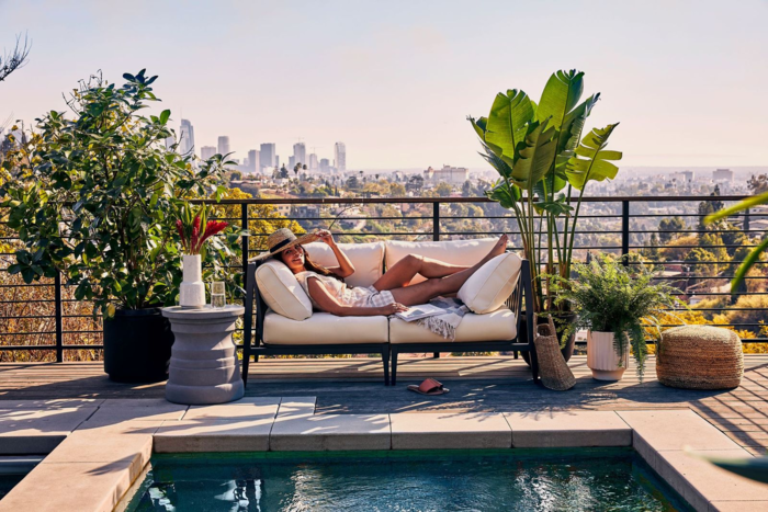 relaxing outside woman with a sunhat lying on a garden bench smiling and relaxing surrounded by plants