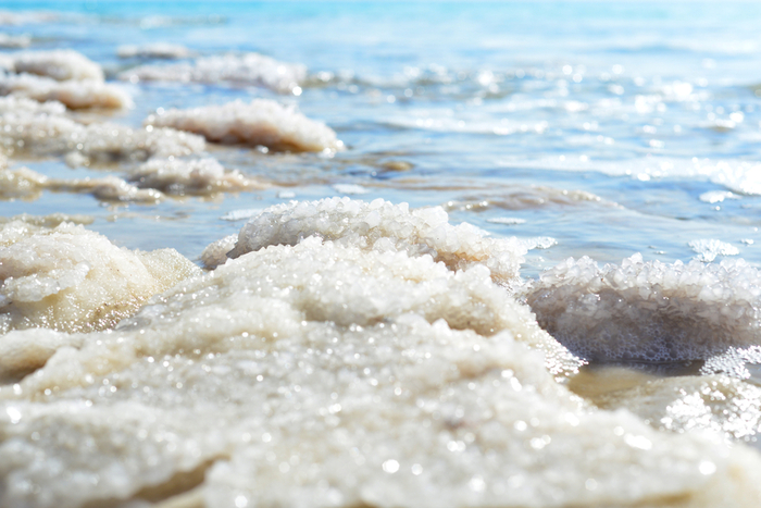 Salt on the shore of the Dead sea blue water in the background