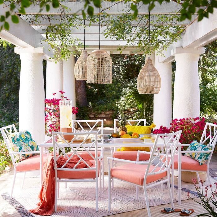 stylish white furniture with colorful cushions and throws rattan lighting fixtures hanging from a white ceiling between large columns