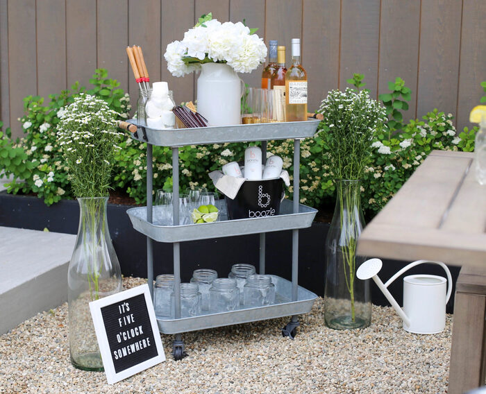 summer bar cart in grey with white flowers wine bottles and glasses in a yard
