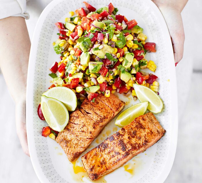 summer salmon woman holding a white plate with freshly baked salmon fillet slices of lemon and fresh salad