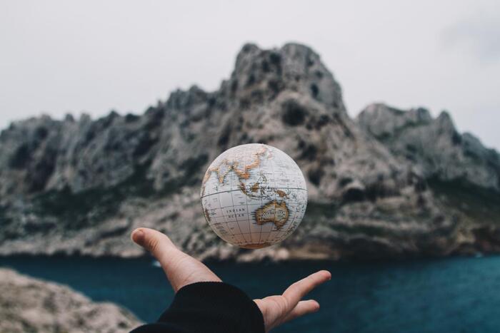 a hand throwing a little globe with rocks in the background