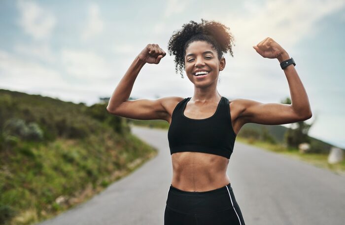 woman dressed in black sportswear working out outdoors showing off her strong arms