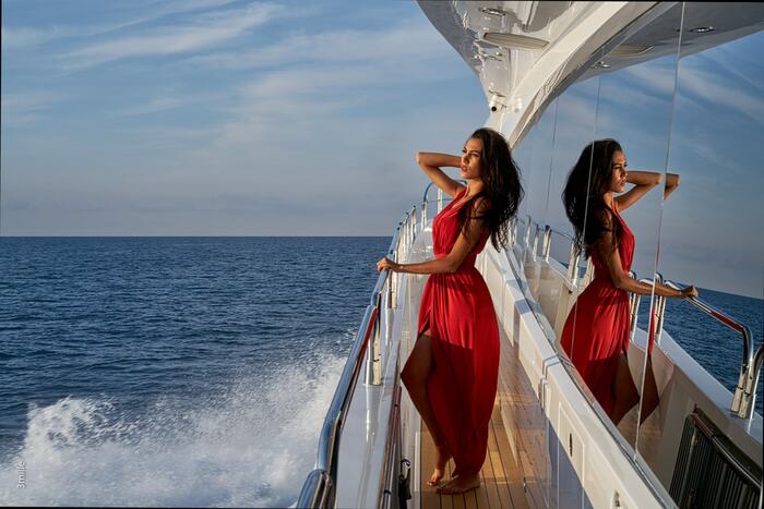 woman in a long red dress with dark hair enjoying her ride on a white yacht