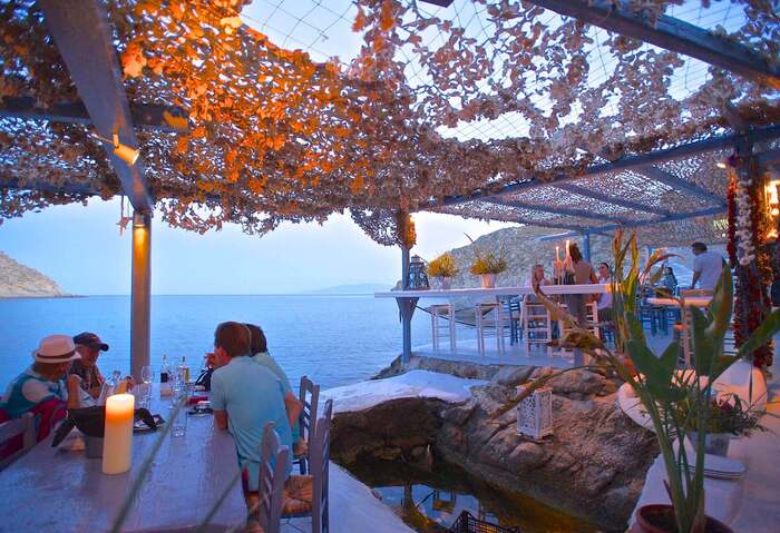 Spilia Seaside Restaurant and cocktail bar on Mykonos on a rock overlooking the sea with people sitting at the tables