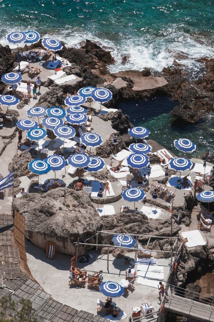 beach bar in Italy on a rocky cliff with a lot of blue and white parasols