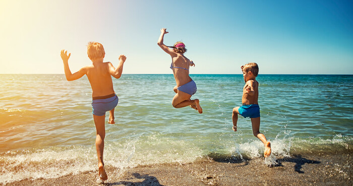 beach fun three children jumping in the water from the beach having fun