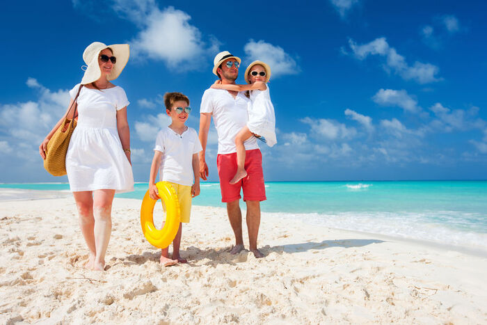 family of four on a white sandy beach enjoying a vacation