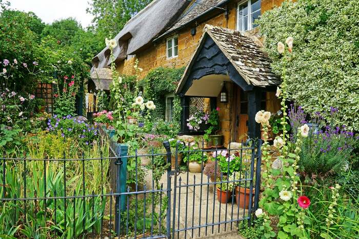 english cottage with a countryside garden in front and a fence