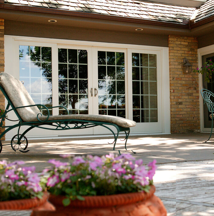 elegant white glass doors shot from a pretty outdoor space with flowers and lounge chair