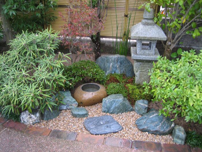 japanese design in a small garden corner with large stones water bowl stone stone lantern and bushes