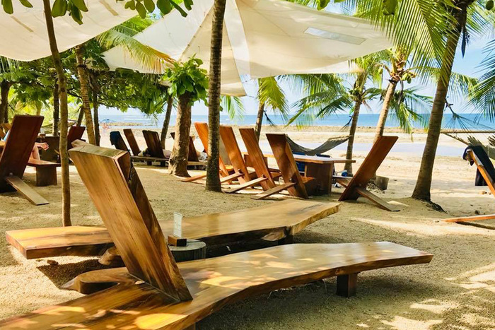 Lola's beach bar with wooden lounge chairs and palm trees