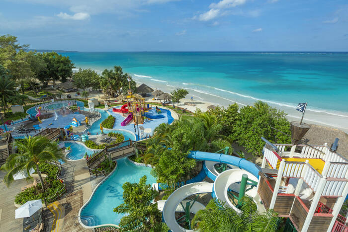 negril resort and spa aqua park with exotic plants and the ocean next to it