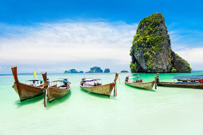 phuket thailand traditional wooden boats in clear waters with large rocks in the background
