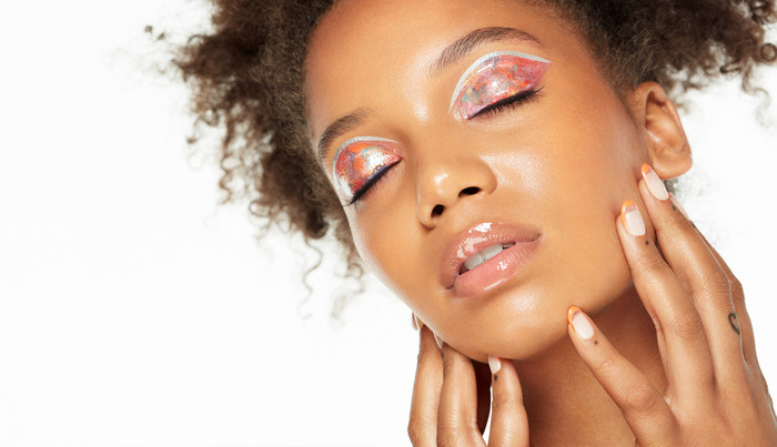summer make up woman with afro hair and pretty pink artistic make up closing her eyes showing her make up