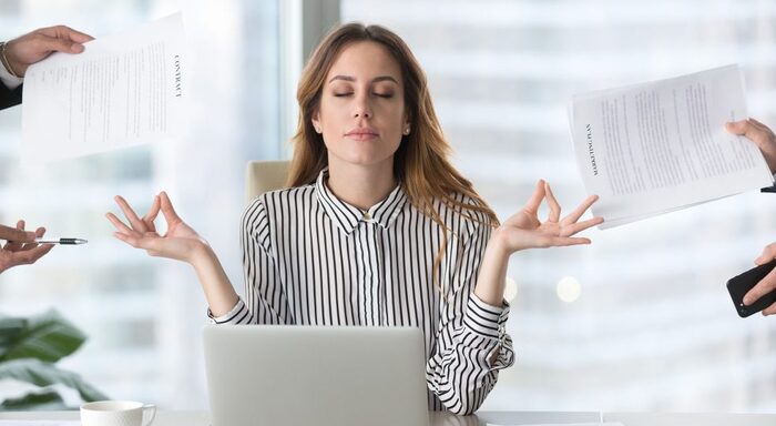 woman in a black and white striped shirt in front of a laptop in yoga pose with hands around her holding papers to sign