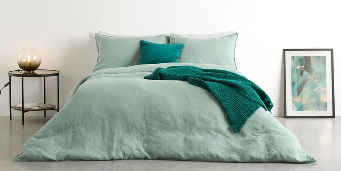 linen bedding in a mint green in a minimalist white space 