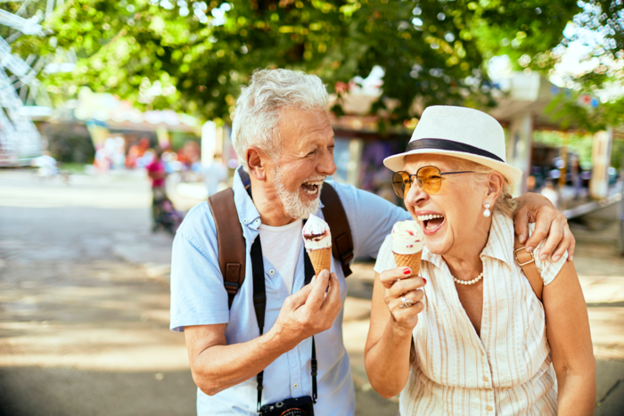 elderly couple on a trip holding ice creams and laughing together