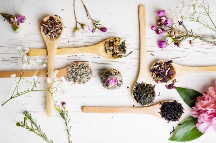 wooden spoons with dry edible flowers scattered on a white wooden table