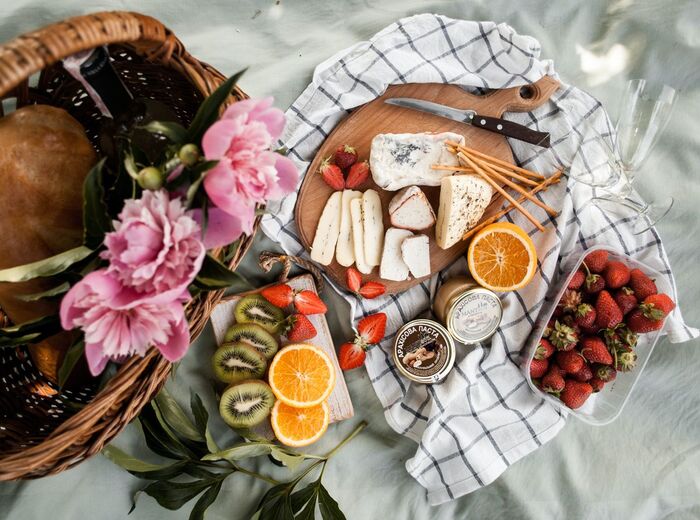 Instagrammable picnic spread with a woven basket and plates with cheese and different fruits