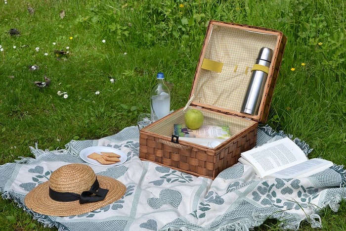 pretty picnic with a vintage basket a hat and an open book on a blue and white blanket