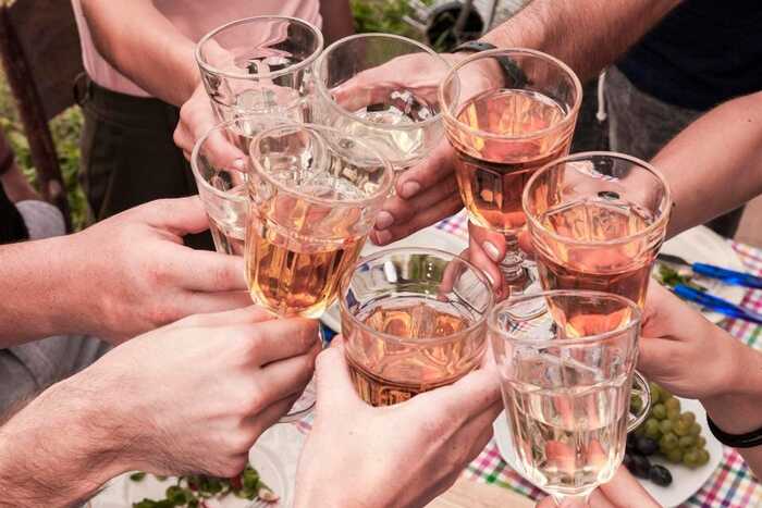 people's hands cheering with glasses of rose outdoors