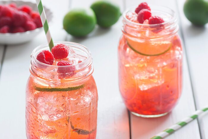 summer cocktail in mason jars with strawberries and lime in the background