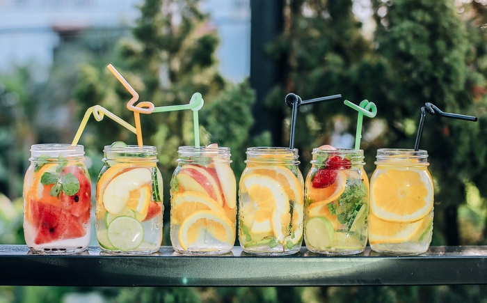 summer drinks soft in mason jars with flexible straws on them filled with different fruits