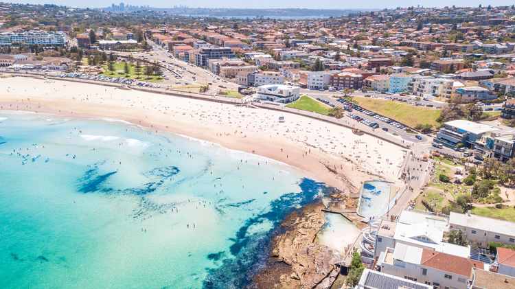 Bondi beach from above with houses in the background and clear light blue water
