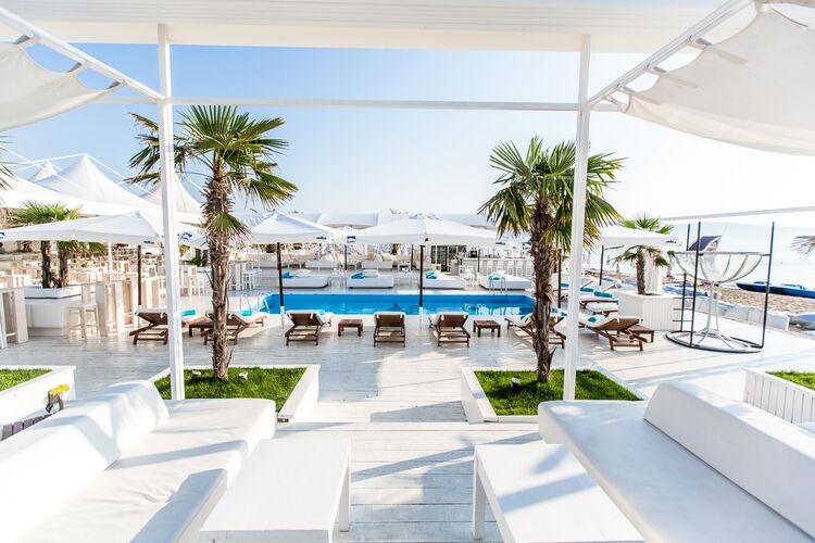 top-rated beach bar all in white with two palm trees and pergolas