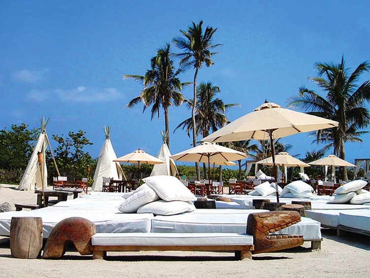 Nikki beach luxurious beach bar with parasols and palm trees in the background
