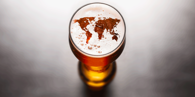 beer world a tall glass filled with beer on a grey background with the world map on the foam