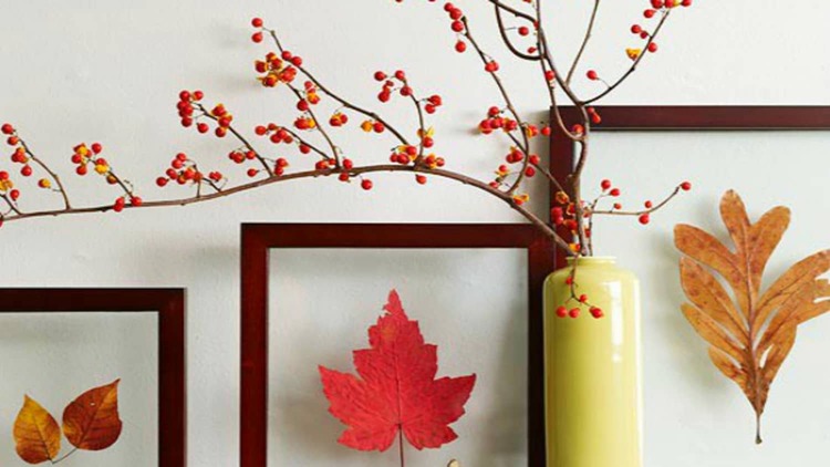 branch with red berries on it in a tall yellow vase and fall leaves in frames