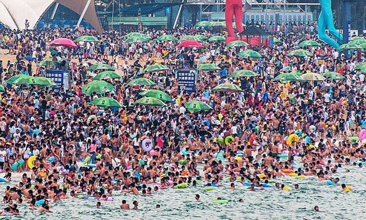 dimeisha beach in china crowded with people and green parasols 