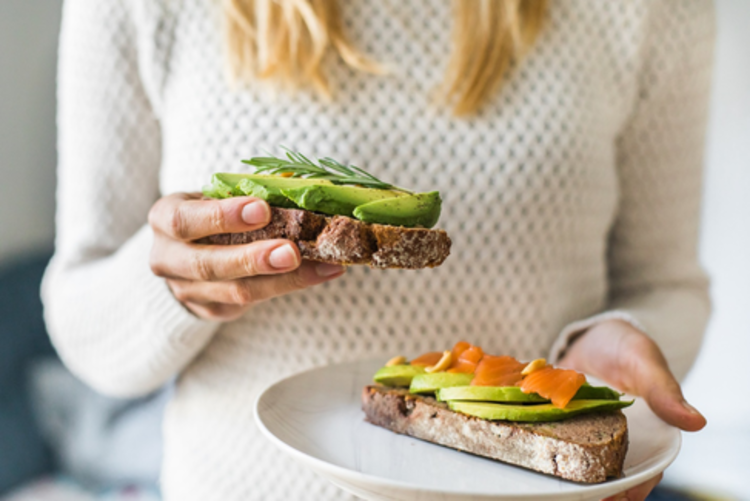 eating healthy diet woman in a pullover with two toasts with avocado in a plate