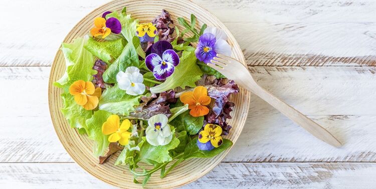 edible flowers in a large salad bowl with a wooden spoon 