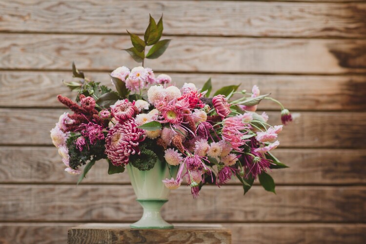 pink flower bouquet in a green vase on a wooden background