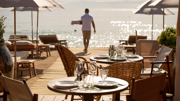 beach bar in St. Tropez with elegant furniture and a man in the background carrying towels