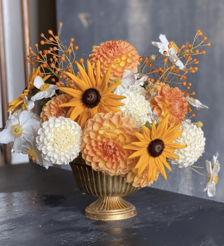 elegant flower arrangement with different Chrysanthemums in orange and white in a metal vase on a dark surface
