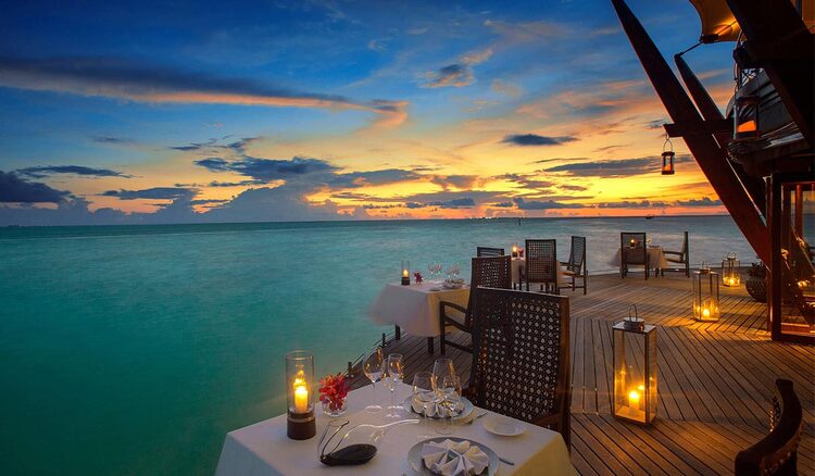 lighthouse restaurant Maldives a terrace overlooking the water lit by lanterns and small elegant tables