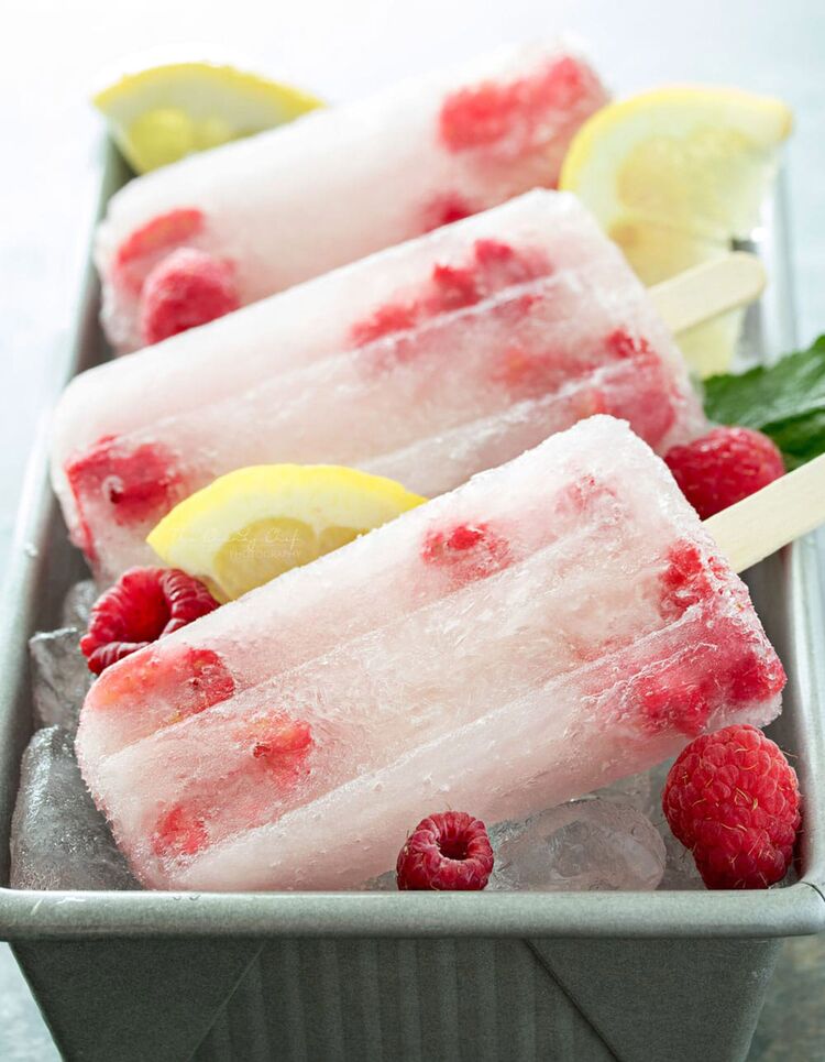 baking form filled with ice and three popsicles with frozen fruits in them