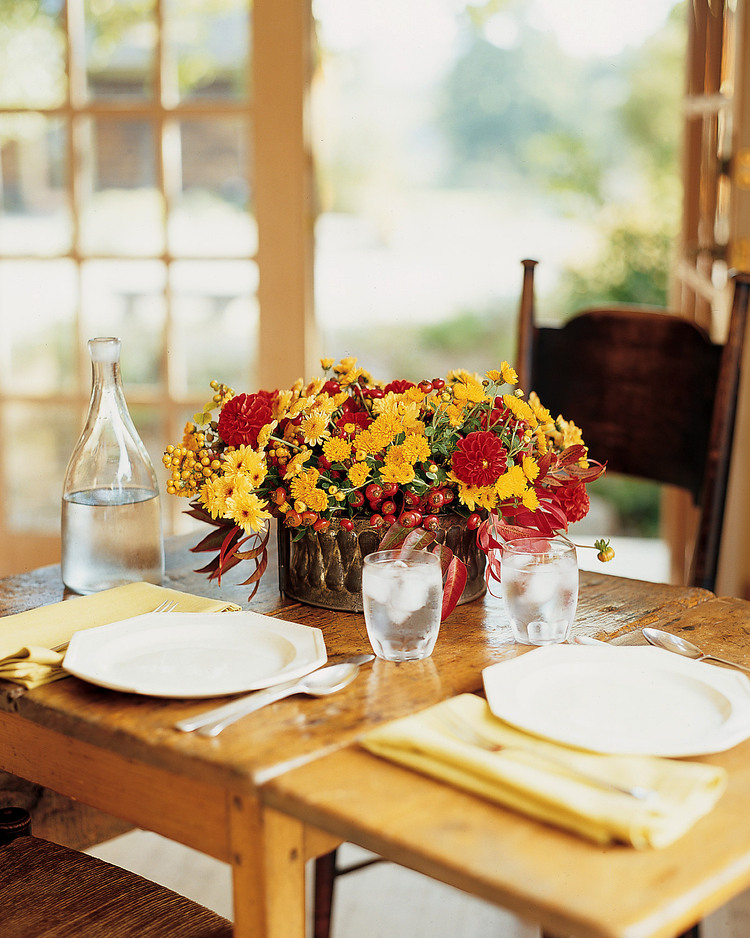 yellow and red chrysanthemum table décor flower arrangement with rose hip on a wooden table