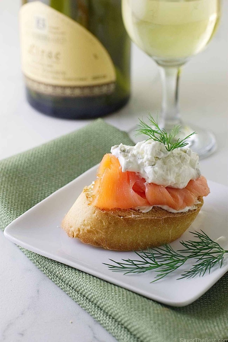 appetizer with smoked salmon and dill paired with white wine in a bottle and a glass on a light green napkin
