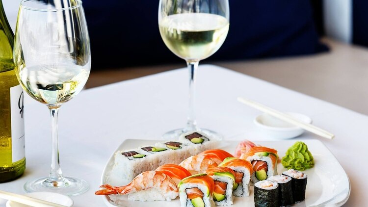 sushi rolls and wine on a white table two elegant glasses of white wine 