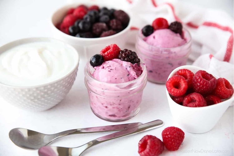 yogo ice berries in small bowls filled with yoghurt and two tea spoons 