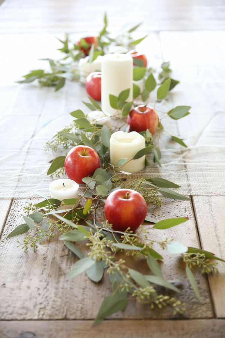 apple runner in the middle of a wooden table with white candles sticking from it