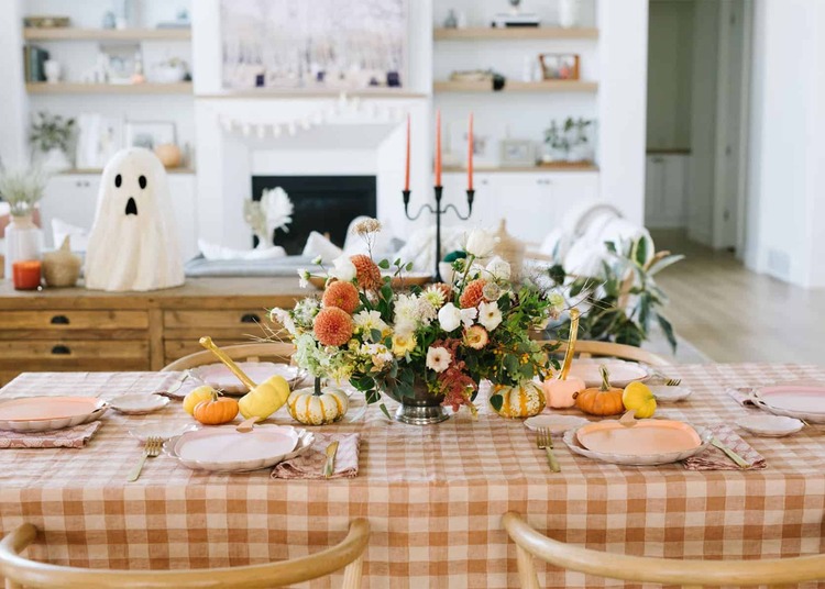 gingham style table cloth on a festive dining table in a living room with pumpkins and flowers on it