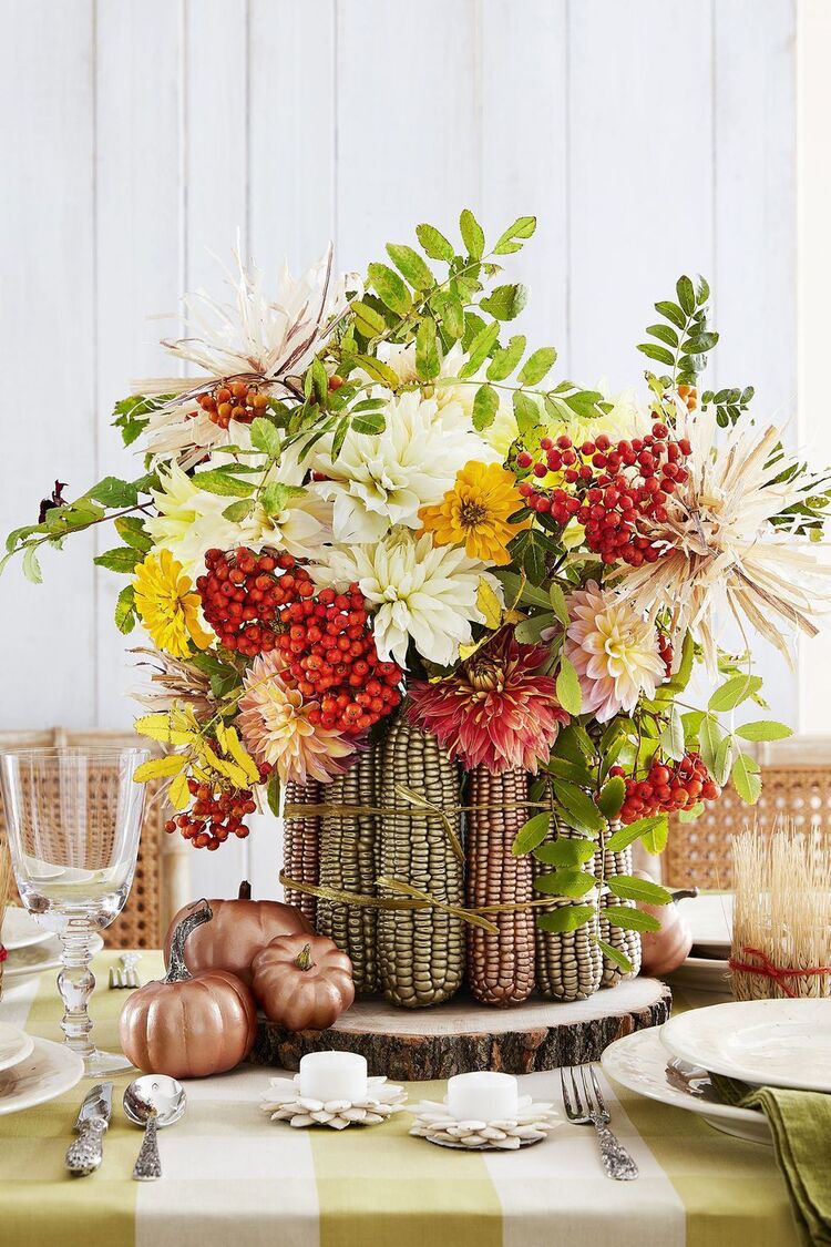 thanksgiving centerpieces made of corn husks and flowers on a table with small pumpkins and festive decorations