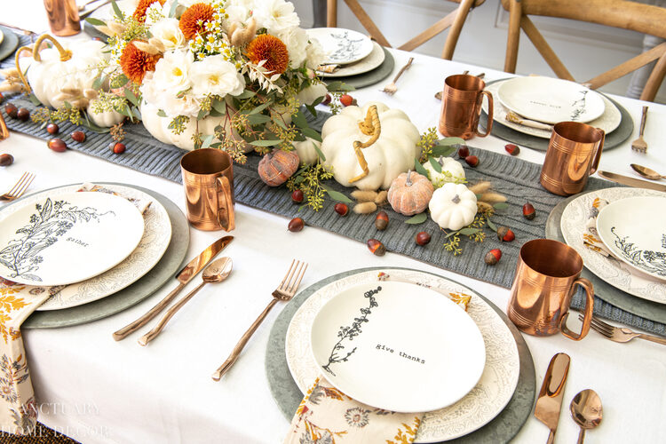 thanksgiving decor inspiration table with brass cutlery and cups and a floral table runner decorated for Thanksgiving