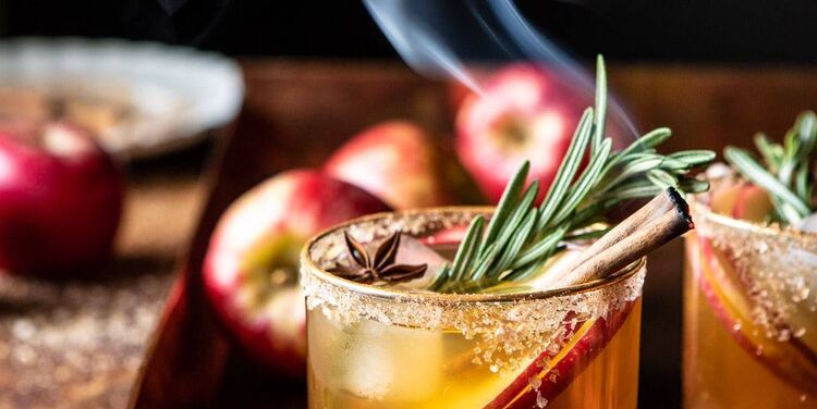 thanksgiving drinks cocktails with rosemary apple and cinnamon with red apples in the background